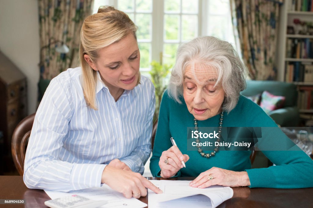 Woman Helping Senior Neighbor With Paperwork